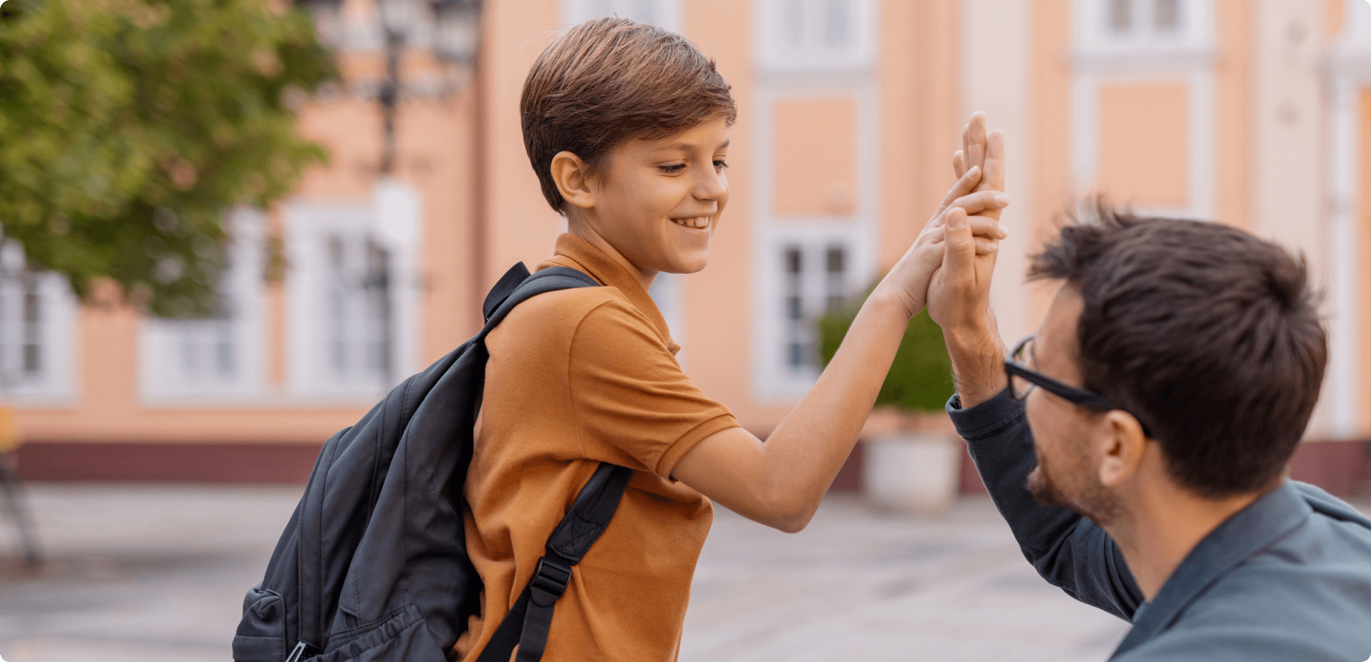 a young boy high-fiving an older male adult, most likely a teacher