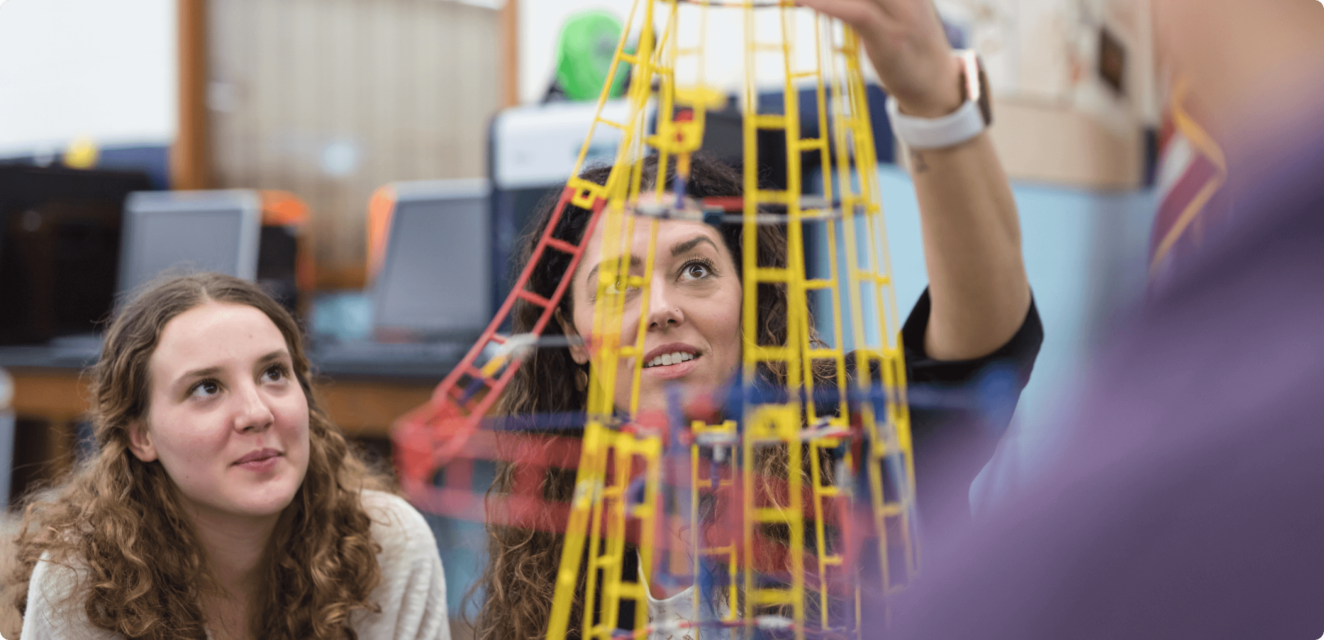 an older teenage girl with her teacher looking at an out of focus plastic roller coaster model