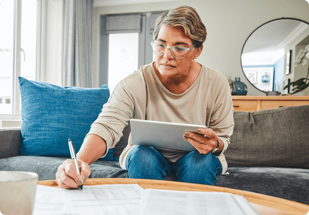 an older woman sitting on a couch filling out donation paperwork