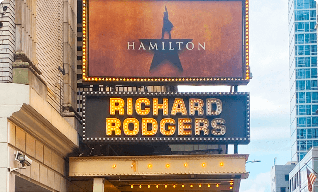 image of outside of a theater advertising a production of Hamilton, with Richard Rodgers in lit up letters