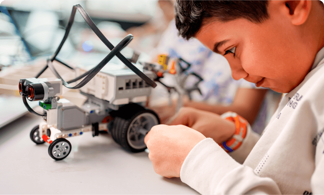 a young boy staring intently at a toy vehicle he is building