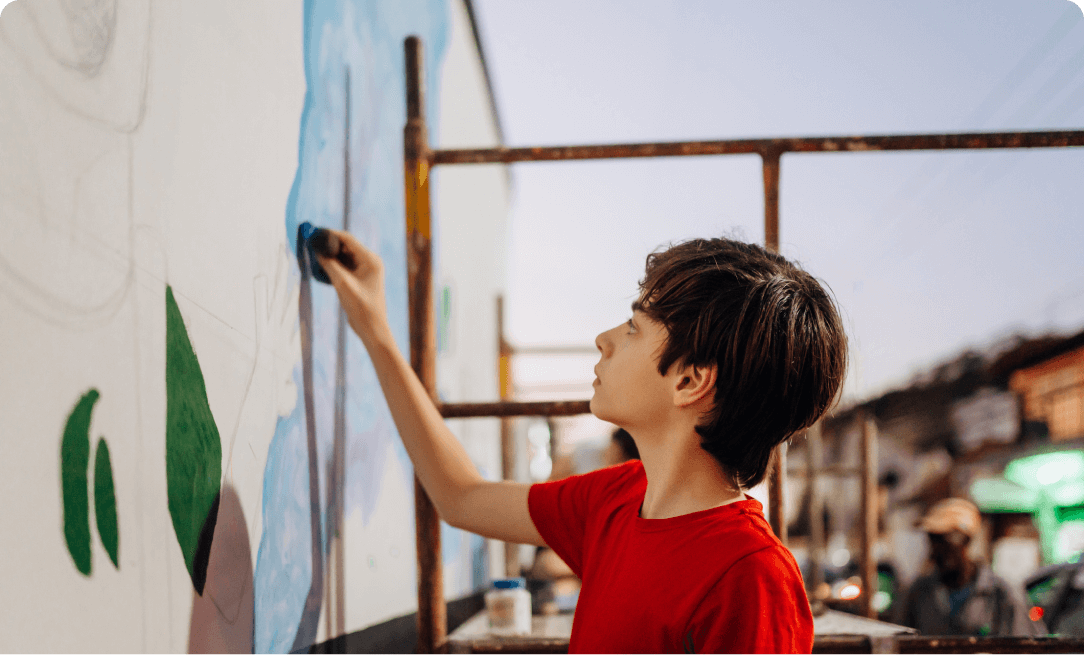 a young male adolescent expressing creativity through painting a wall