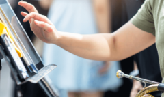 close up image of a young student's hand hovering over a tablet on a music stand. The student is holding a french horn