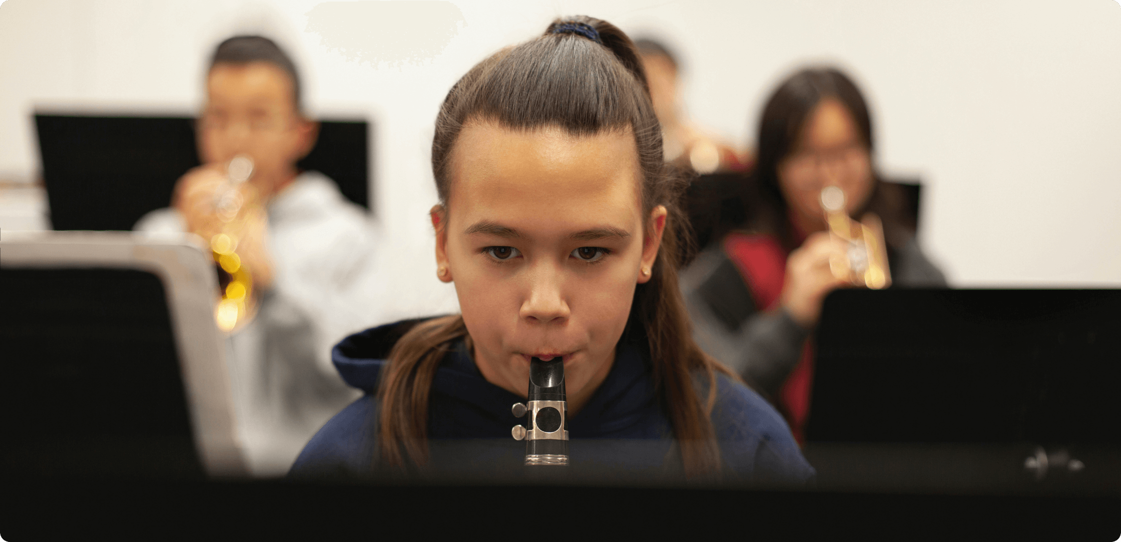a young girl with her hair in a ponytail playing the clarinet